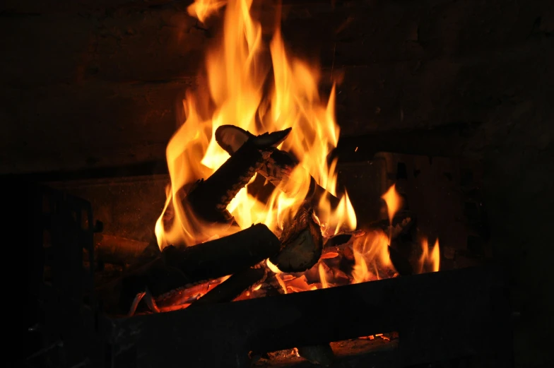 a log fire burning in a fireplace with bright orange flames