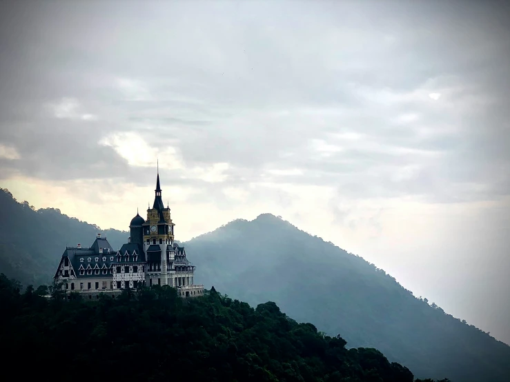 a castle atop a hill with a cloudy sky