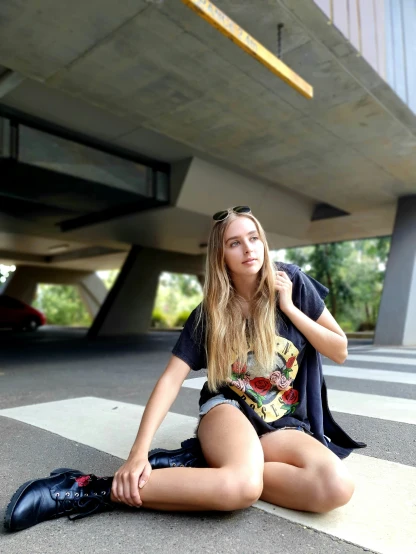 a young lady sitting on the floor wearing a jacket and t - shirt