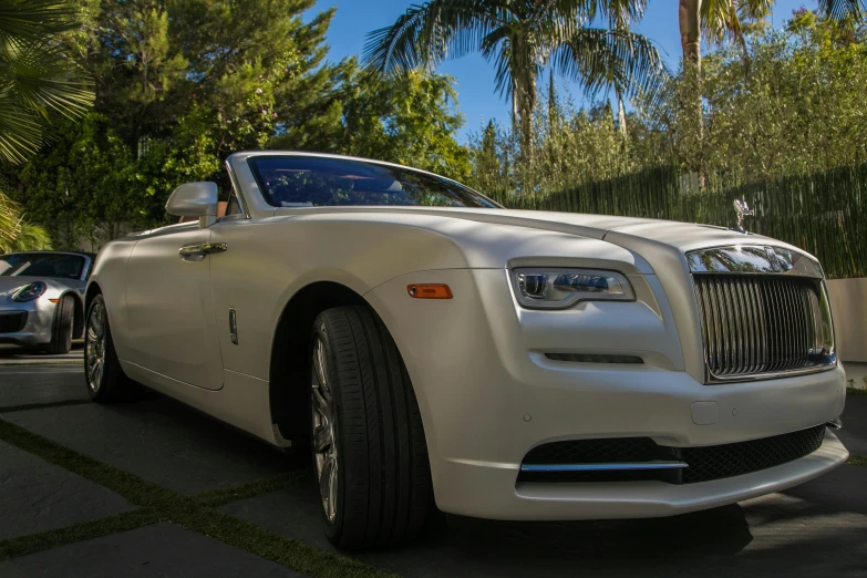 a white rolls royce parked in a driveway