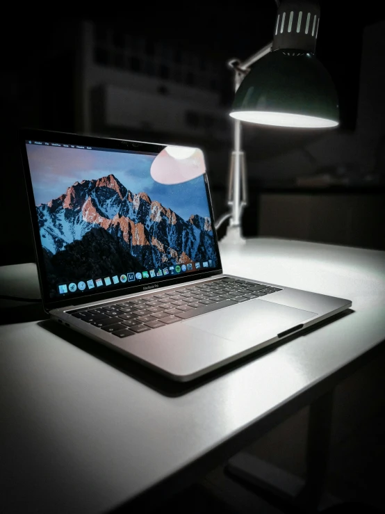 an apple laptop computer on a desk in the dark