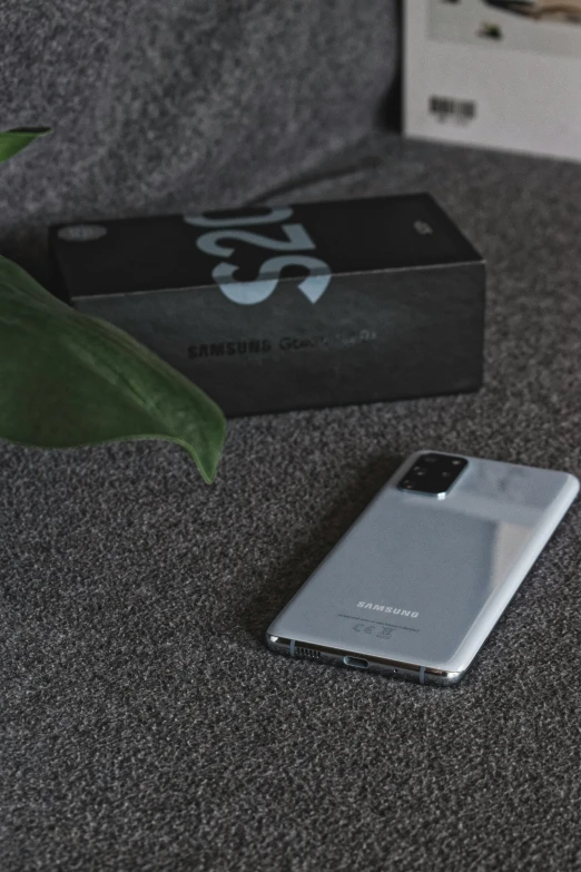 the smartphone is lying on the table next to a box