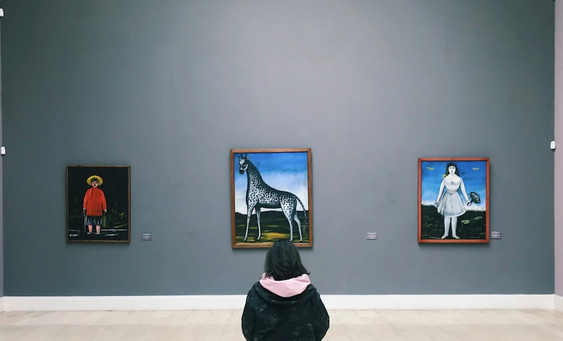 woman looking at several pictures in a museum