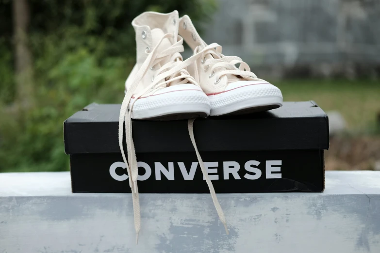 a pair of white converse shoes is sitting on top of the box
