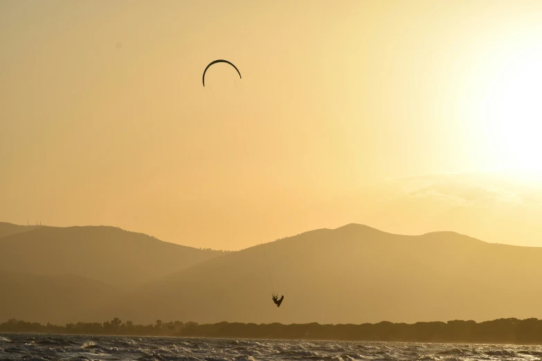 an ocean view with a person windsurfing in the foreground