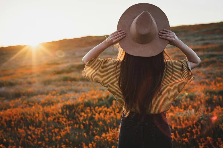 the back of a woman's head standing on top of a field