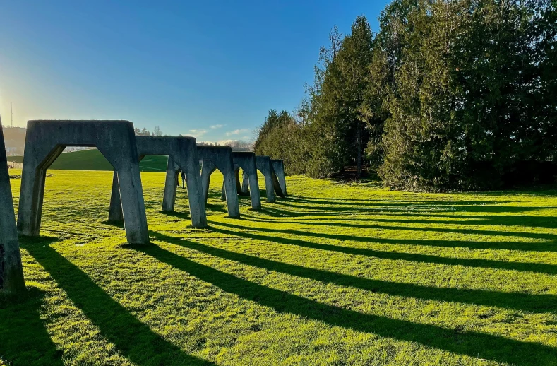 the sun is shining down on some wooden structures in a field