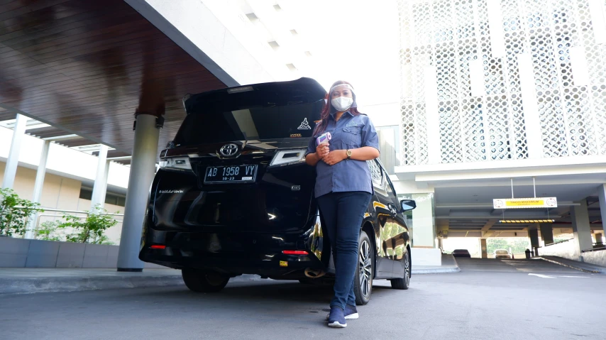 a young lady poses with her cars in a driveway