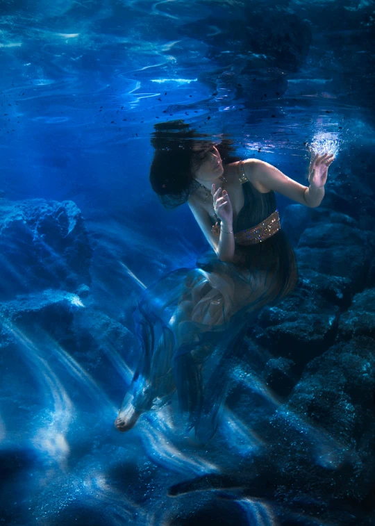an underwater woman in black top holding onto a silver disc