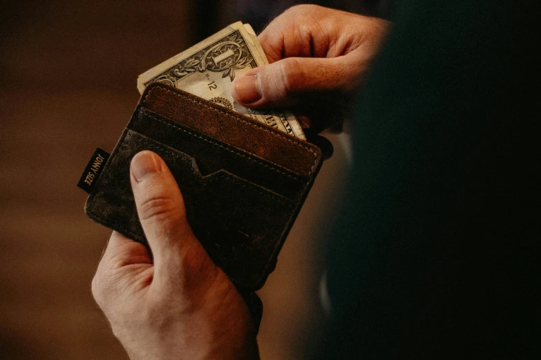 a person holding an open wallet with two dollars