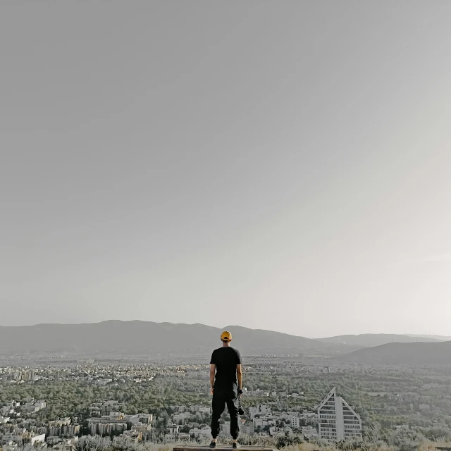 a man in black is standing on top of a hill