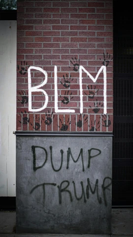 a brick wall with graffiti and a large sign that says blm