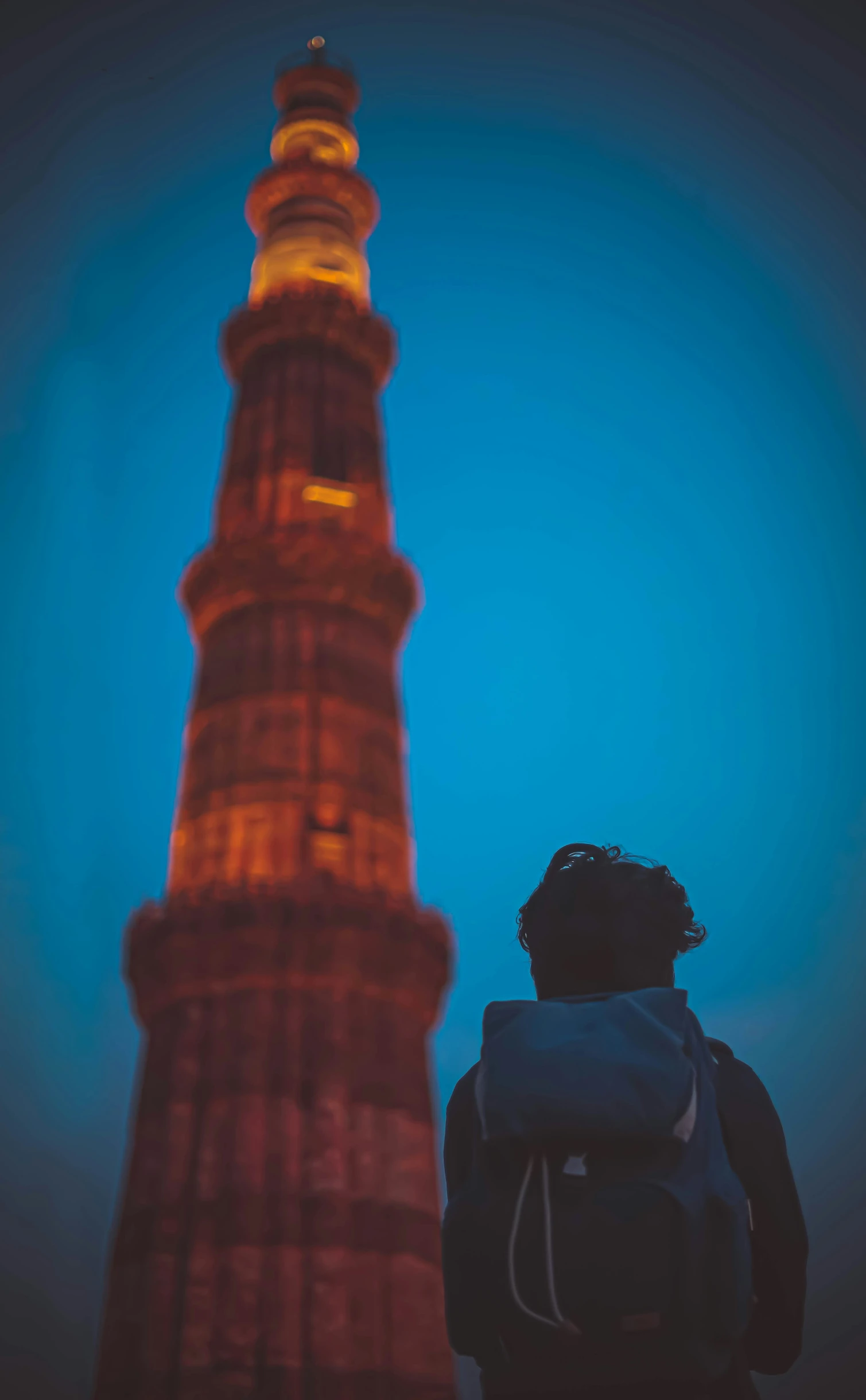 a person standing next to a tall tower in the sky