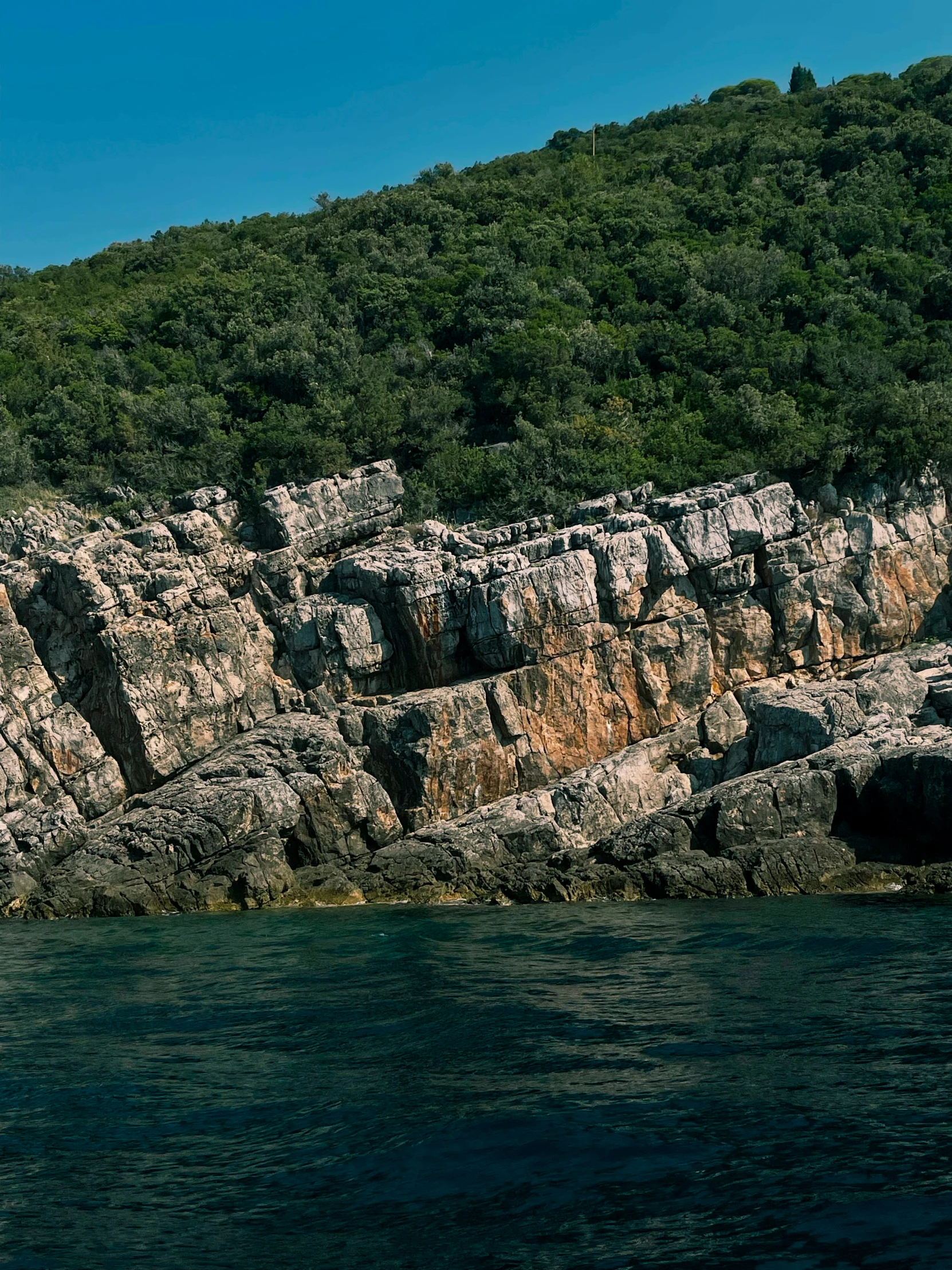 there are two boats in the water by the rocky shore