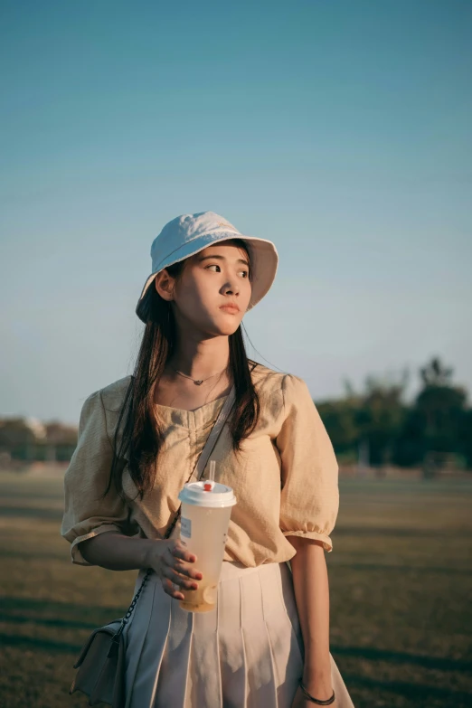 young woman standing in a field with her hand on the cup