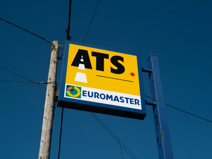 an at's sign hangs on a pole against a blue sky