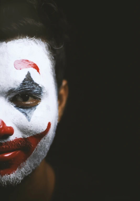 a person is posing with a painted clown mask