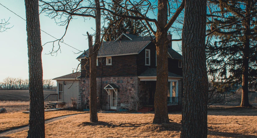 an old brick house with trees on the foreground