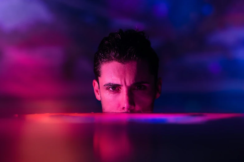 a man staring in a water with purple and blue lights
