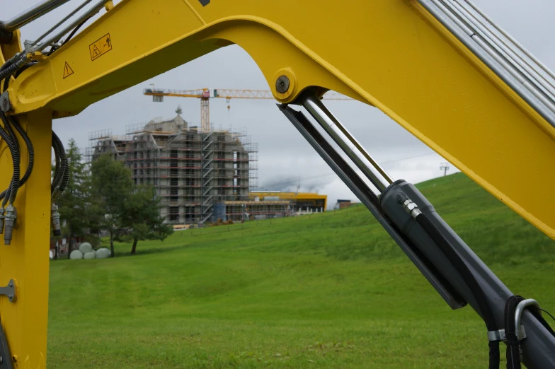 a very large yellow crane is on a grassy field