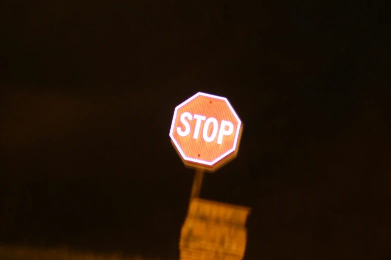 a stop sign with street signs glowing in the night
