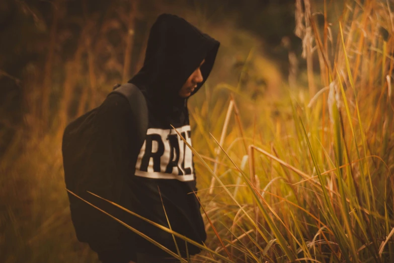 hooded man in a field using cell phone