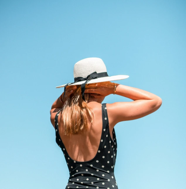 a woman is wearing a polka dot bathing suit with her hair in a ponytail