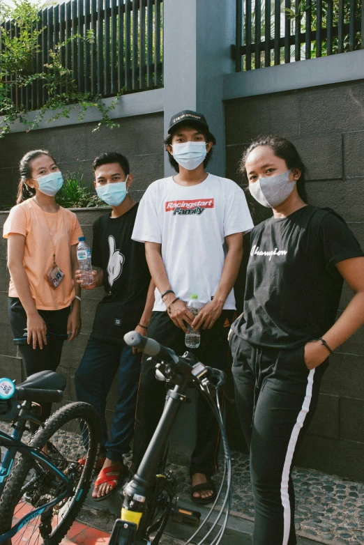 four s in a group with faces masks and bicycles