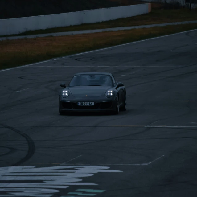 a porsche sports car driving on a track at dusk