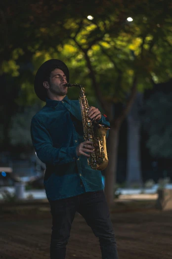 man playing saxophone outdoors under trees and lights