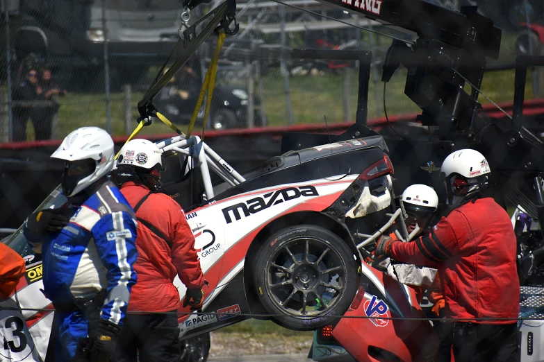 two mechanics attaching a race car on a track