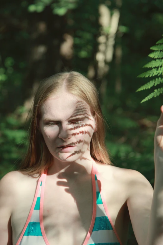 a girl with a pattern on her face holding a leaf