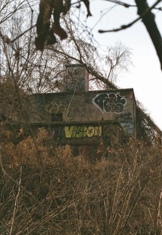 an old building is covered in graffiti next to some trees