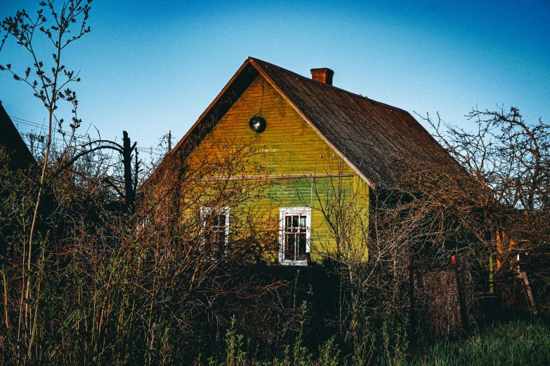 a yellow house with a door and windows next to some bushes