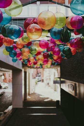 a long hallway with several multi - colored balloons hanging from the ceiling