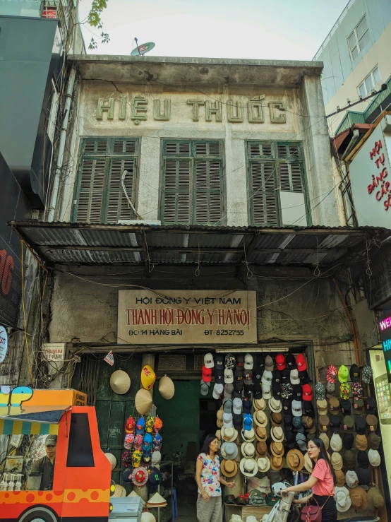 two people are walking by a store with many hanging objects