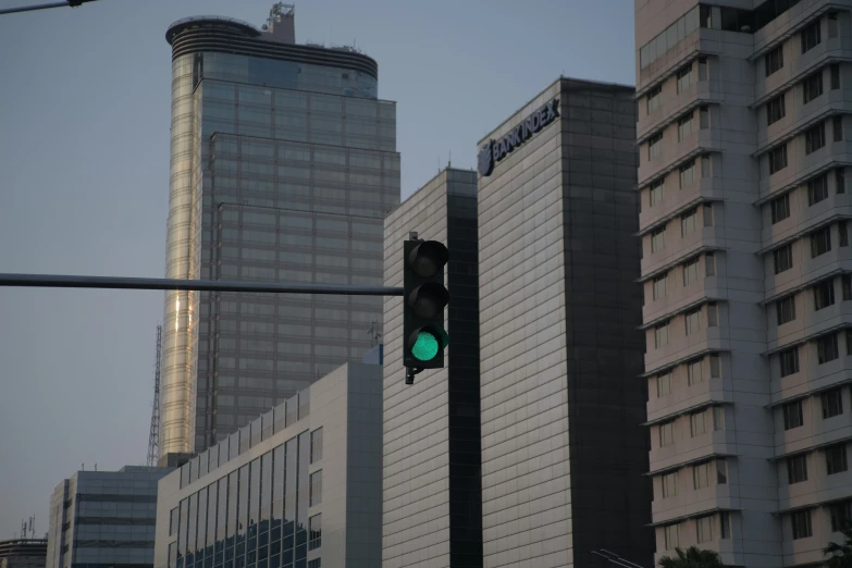 a traffic light with a green traffic signal and building in the background