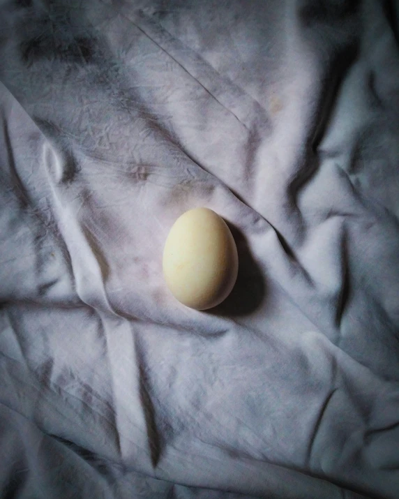 an egg sitting on top of white blanket covered in white material