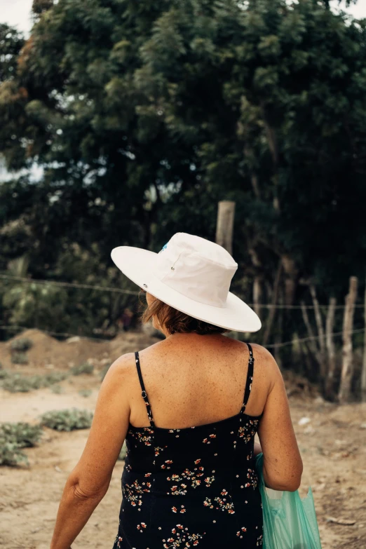 a woman wearing a white hat walking down the street