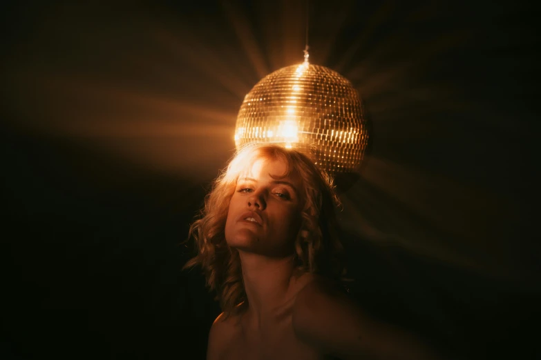 a woman posing with a disco ball above her head