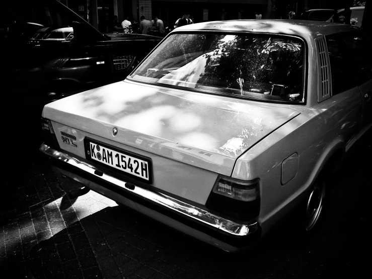 a small old car sitting on the side of a street