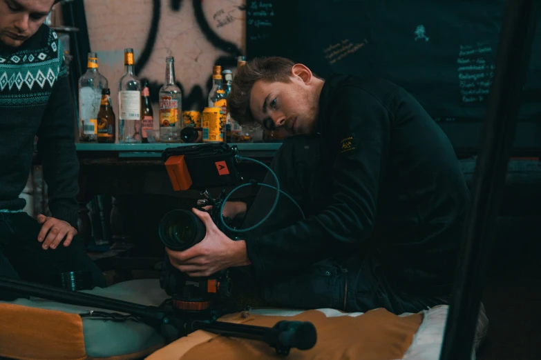 two men on a bed, one holding a camera