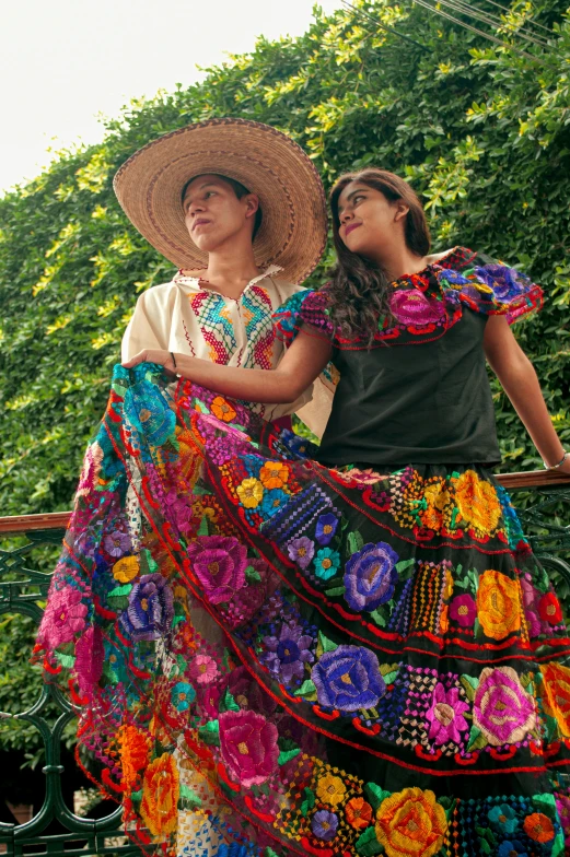 two woman dressed in mexican clothing with floral skirts and hats