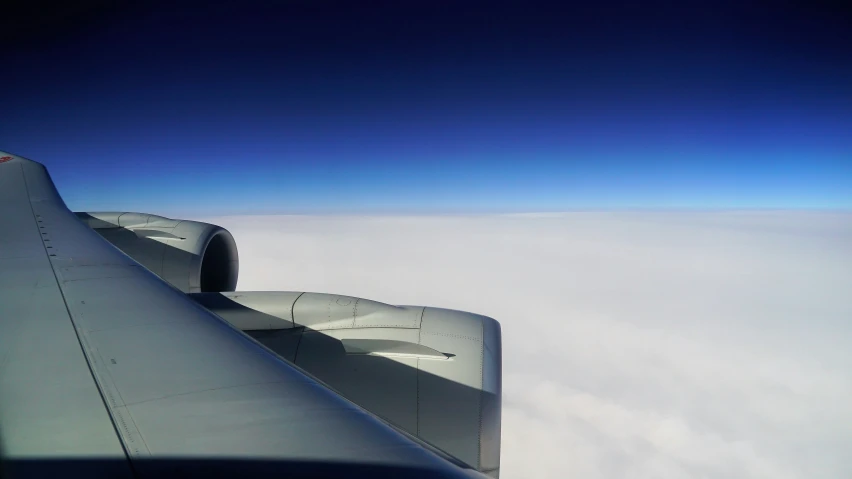 an airplane wing over some clouds on a blue day