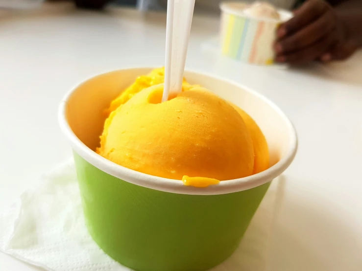 an ice cream in a green and white cup with a spoon