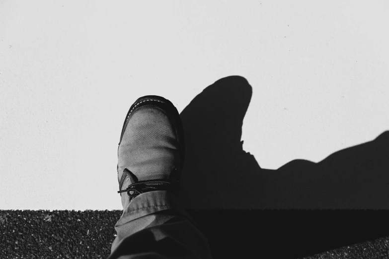 a person standing up in his shadow wearing shoes