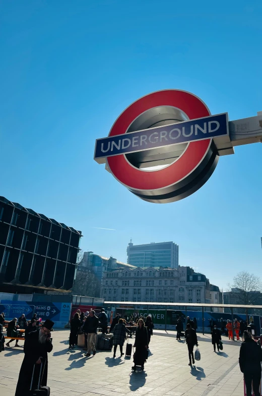 an underground sign over a crowded square in london