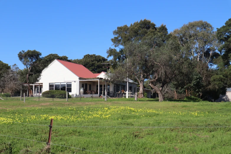 a large white house sits in the middle of the green field