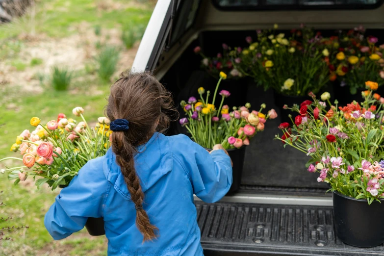 a  standing outside of a car looking at flowers in her hands