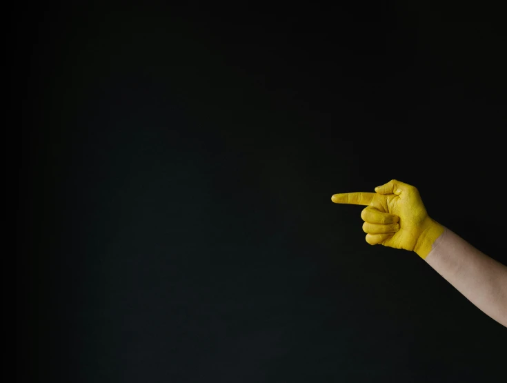 a person wearing yellow gloves pointing towards the camera